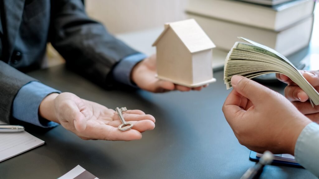 This image depicts a business transaction focusing on a lifetime mortgage. In the foreground, two sets of hands are presented: one hand holds a set of keys, symbolizing property ownership, while the other hand counts a stack of cash, suggesting a financial transaction.